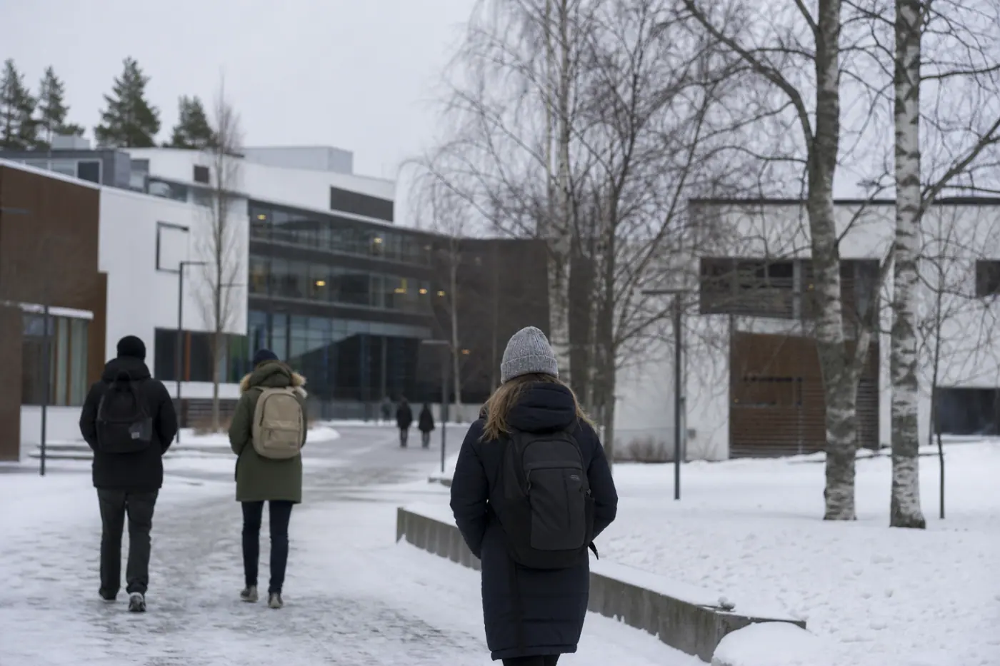 Talvinen yliopistokampus, jonka modernien rakennusten edustalla näkyy muutama epätarkka ihminen.