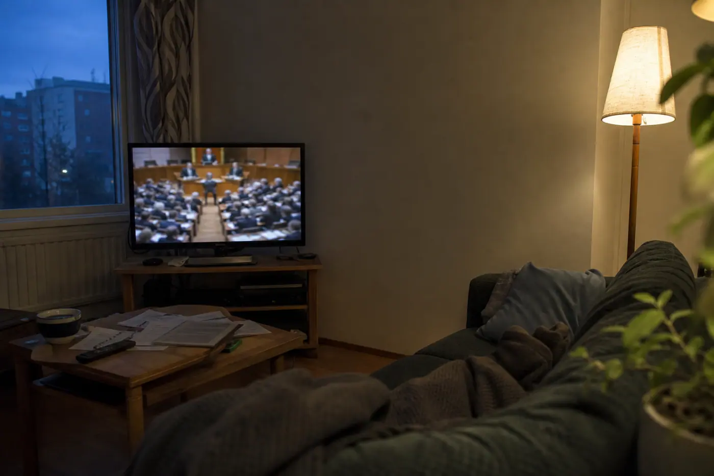 Hervantalaisen asunnon olohuoneessa television ruudulla näkyy epätarkka parlamenttikeskustelu, ja pöydällä on papereita.