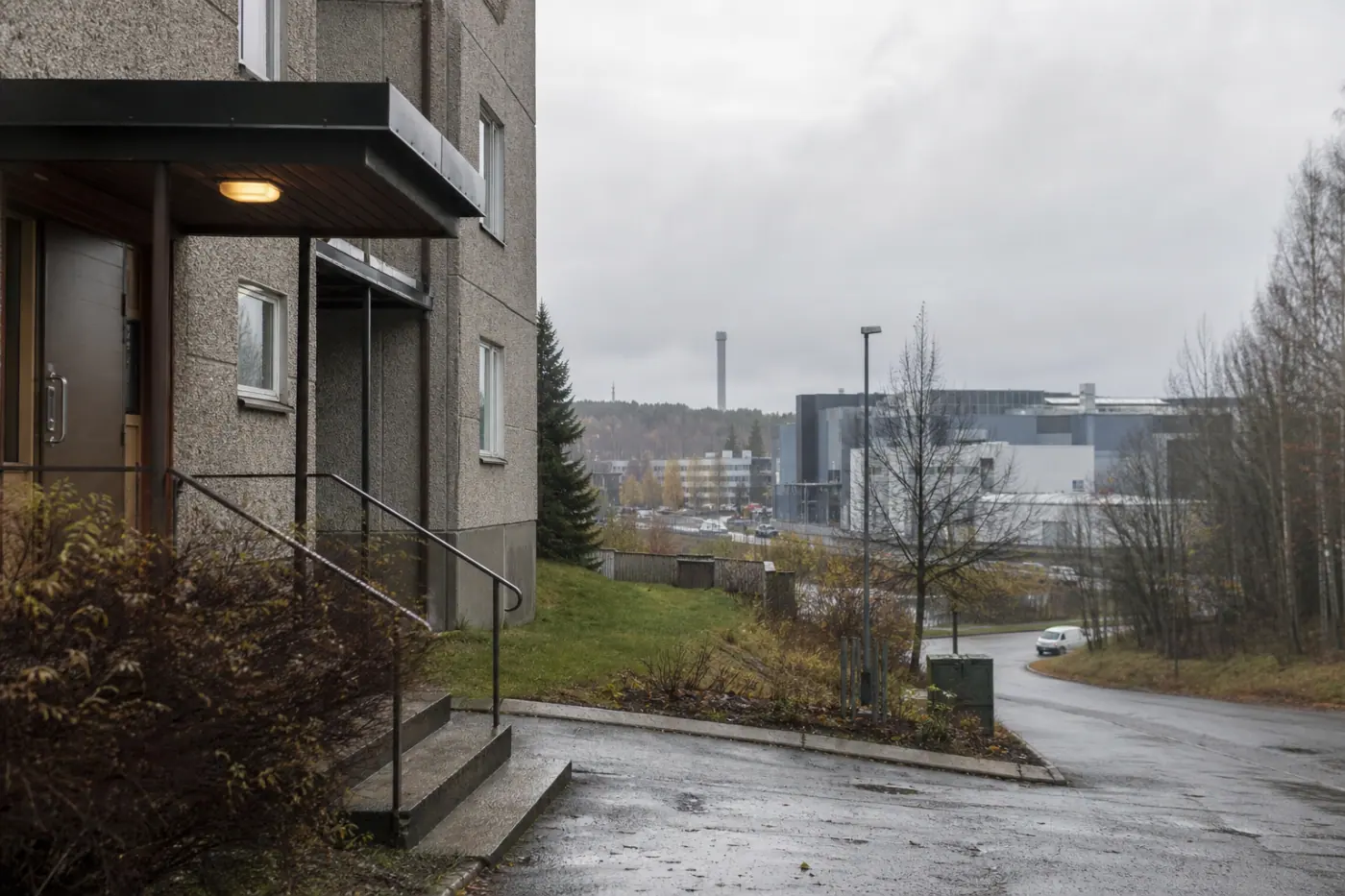Pilvinen kaupunkimaisema Hervannassa, etualalla asuinrakennuksen piha ja taustalla teollisuus- ja toimistorakennuksia.