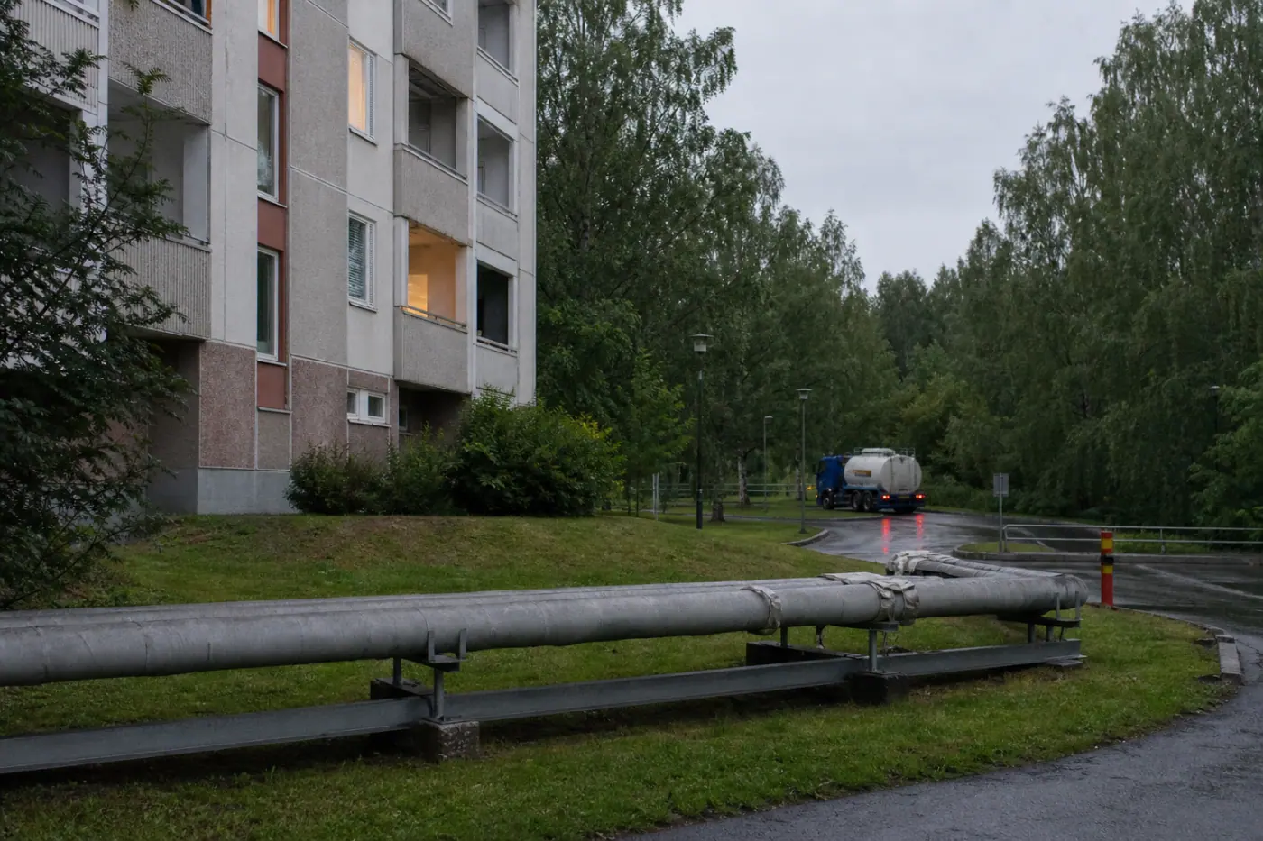 Suomalainen asuinalue Hervannassa viileänä kesäiltana, taustalla kerrostaloja ja lämmitykseen liittyvää teknistä infrastruktuuria.