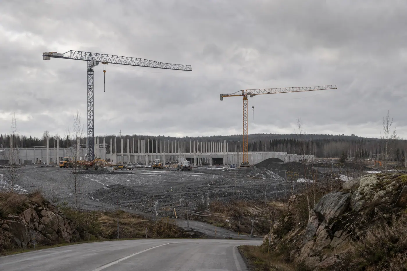 Rakennustyömaa suomalaisessa lähiömaisemassa, taustalla nosturi ja aidattu tontti.