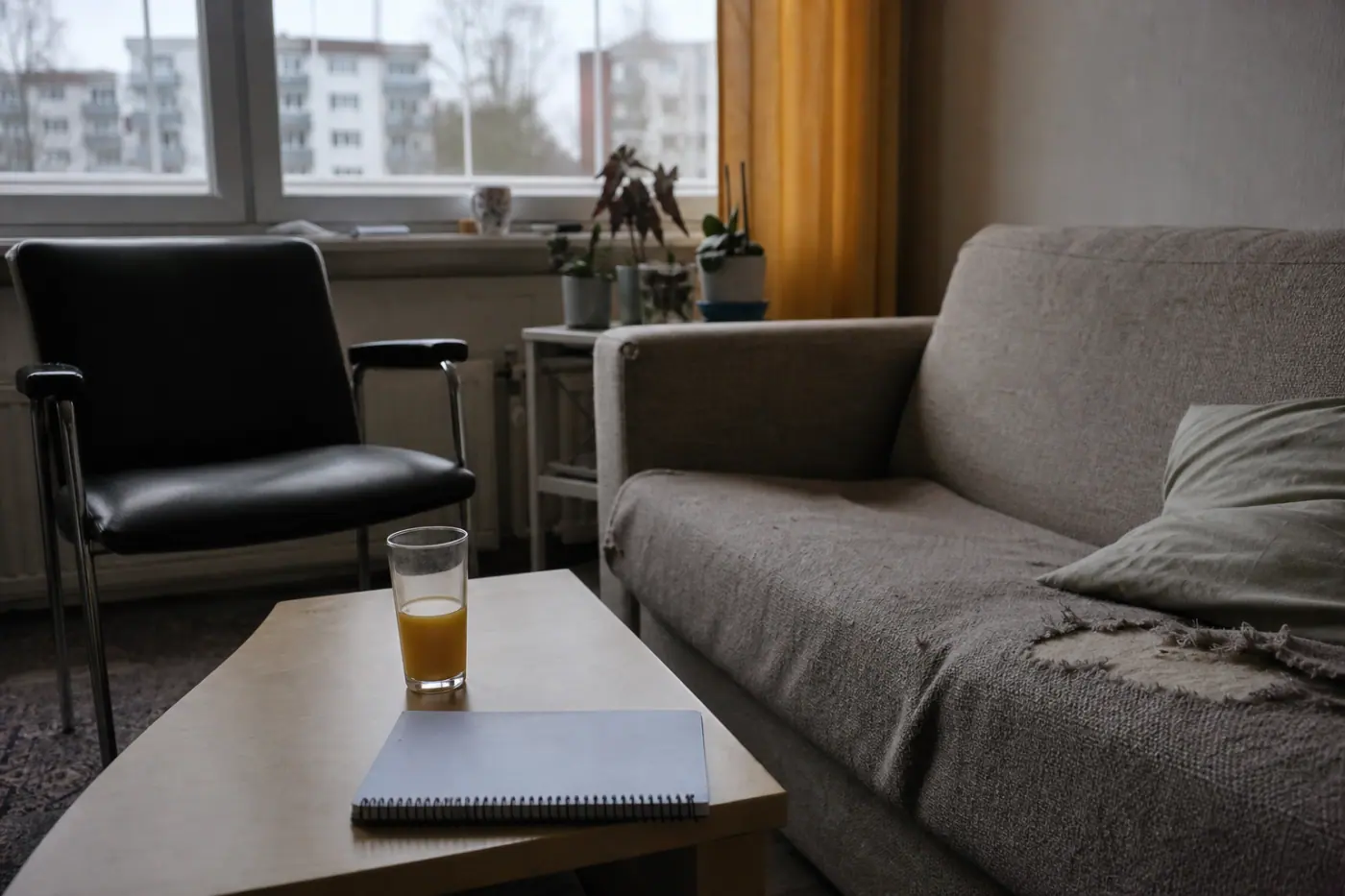 Hervantalaisen olohuoneen sohva, matala pöytä, mehulasillinen ja muistiinpanovihko.