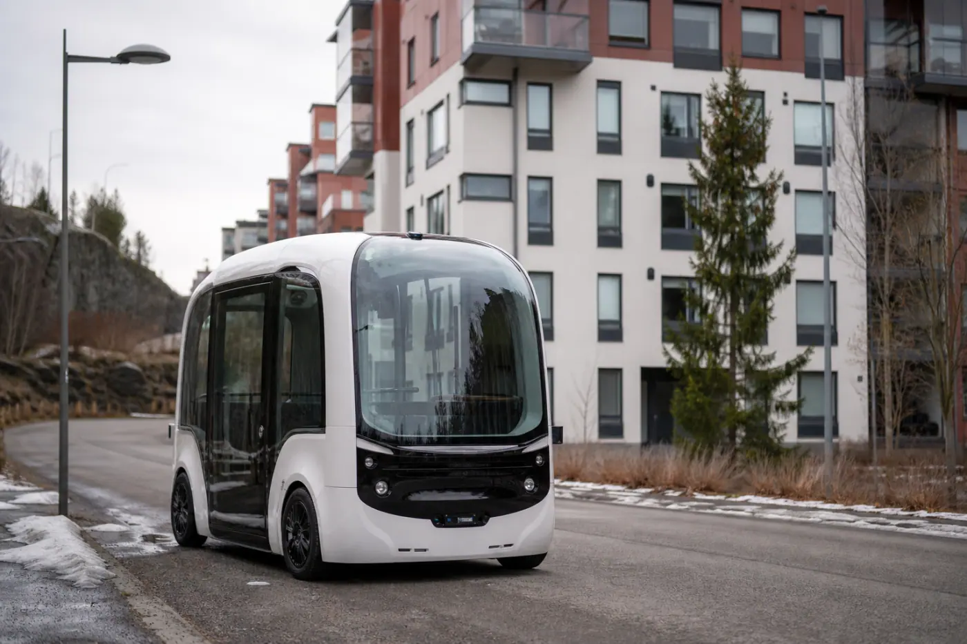 Robottibussia muistuttava moderni pikkubussi ajaa tamperelaisella asuinkadulla kerrostalojen ympäröimänä.