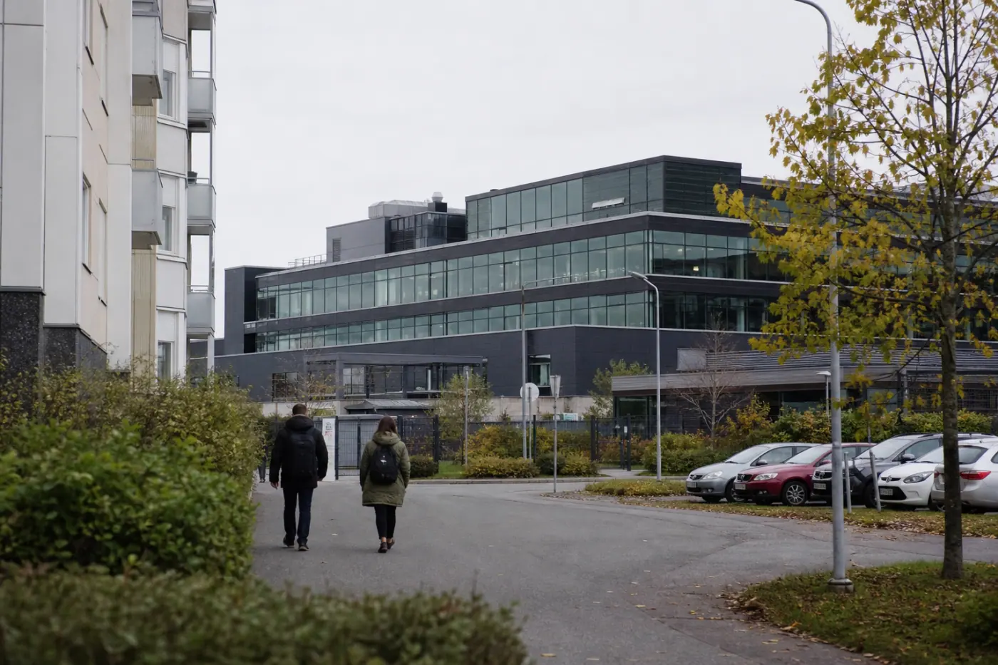 Moderni toimistorakennus Tampereella harmaassa päivänvalossa, kadulla muutama epätarkka ohikulkija.