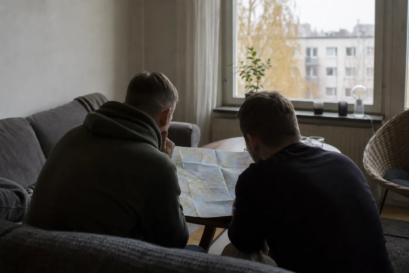 Hervantalaisen olohuoneen pöydällä on liikennekartta, ja kaksi selin kuvattua henkilöä keskustelee sen äärellä.