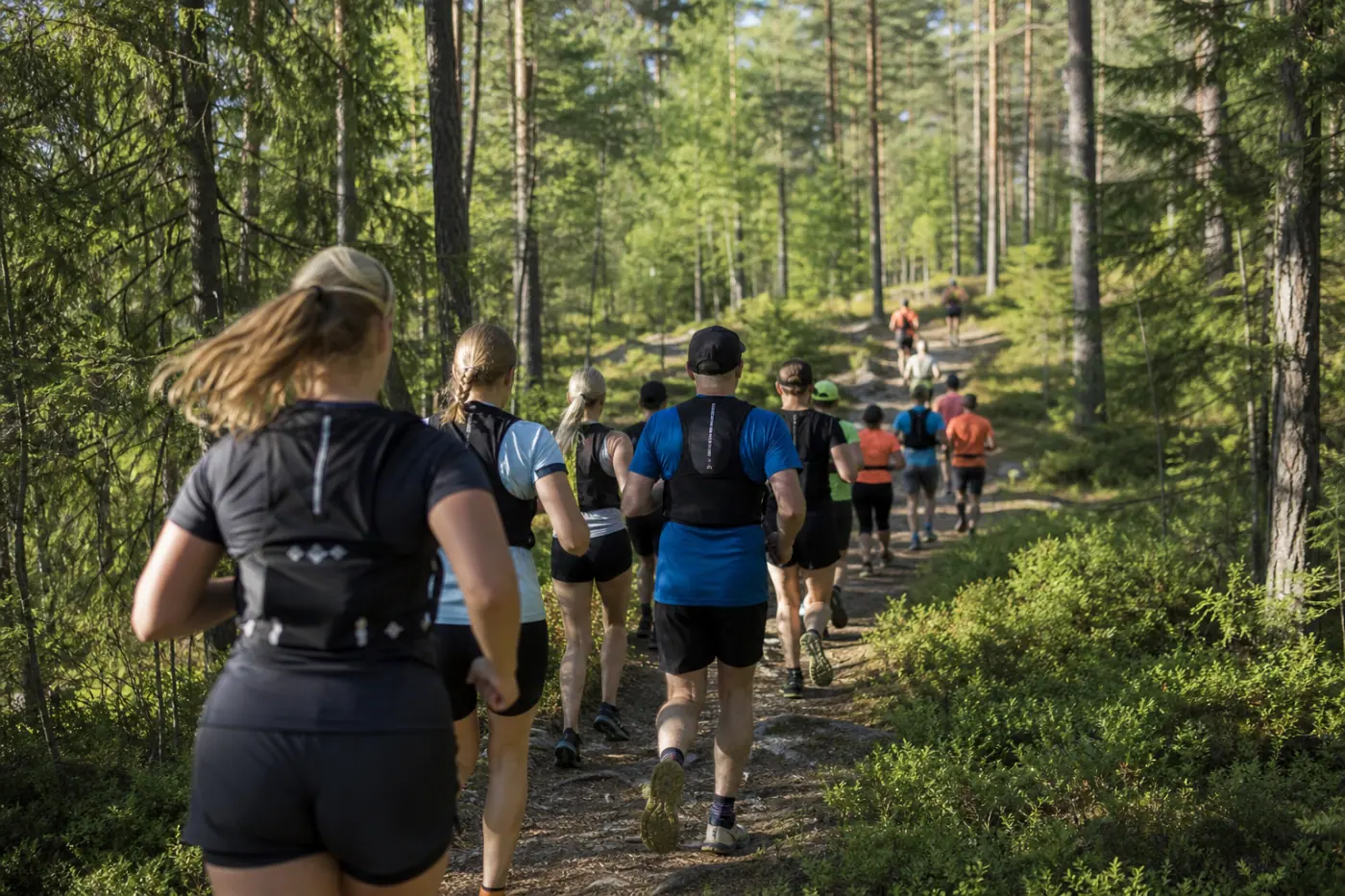 Juoksijoita kulkee aurinkoisella metsäpolulla Tampereen seudulla.