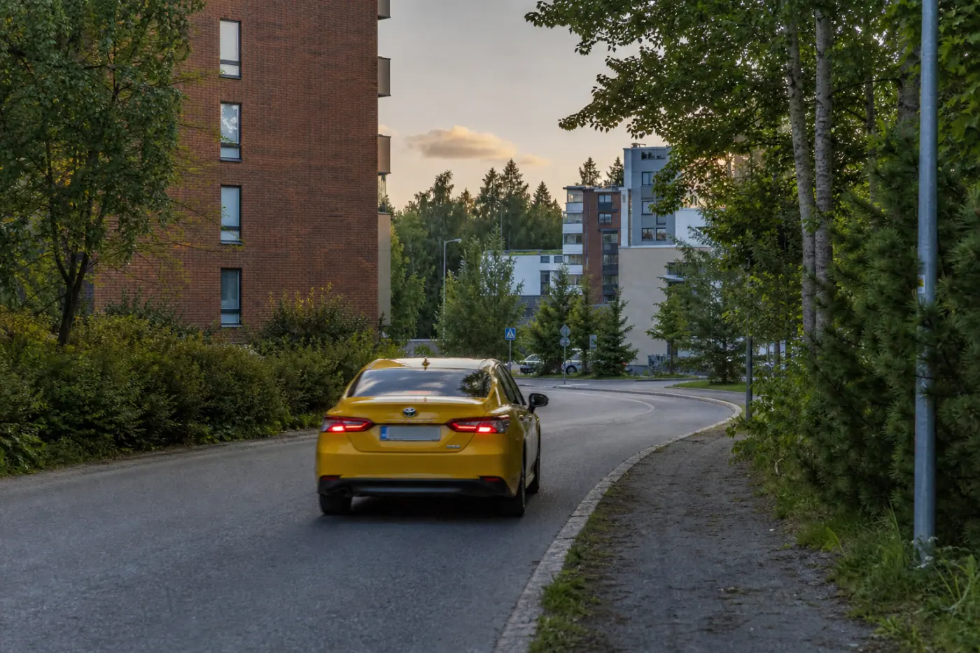 Kesäisellä tamperelaisella asuinkadulla näkyy taksi takaapäin ja taustalla kerrostaloja.